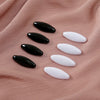 Eight plastic safety pins in black and white oval shapes arranged on a pink fabric.