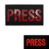 Black embroidered patch with red text spelling PRESS on a fabric background
