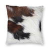A square cushion cover made of faux fur cowhide print featuring brown and white patches.