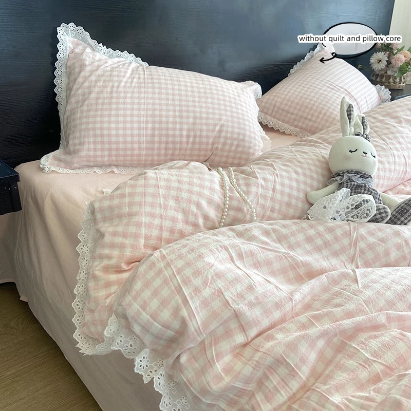 A pink gingham plaid duvet cover and pillowcase set with white lace trim on a bed.