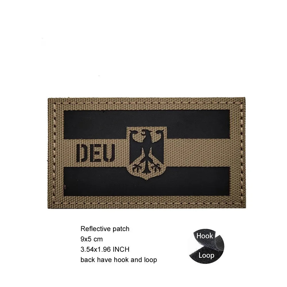 A rectangular beige reflective patch featuring a black banner with the German eagle symbol and text DEU