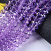 Purple faceted rondelle glass beads strung together on a black background