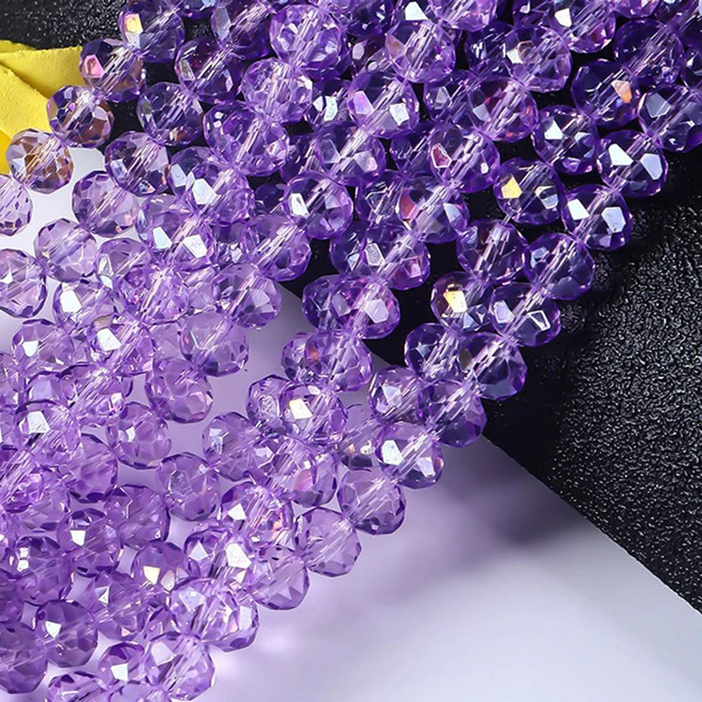 Purple faceted rondelle glass beads strung together on a black background