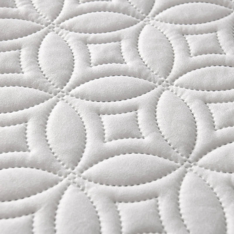 White quilted mattress protector featuring a repeating geometric pattern.