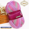 A skein of gradient pink and gray wool yarn is shown next to a wooden box.