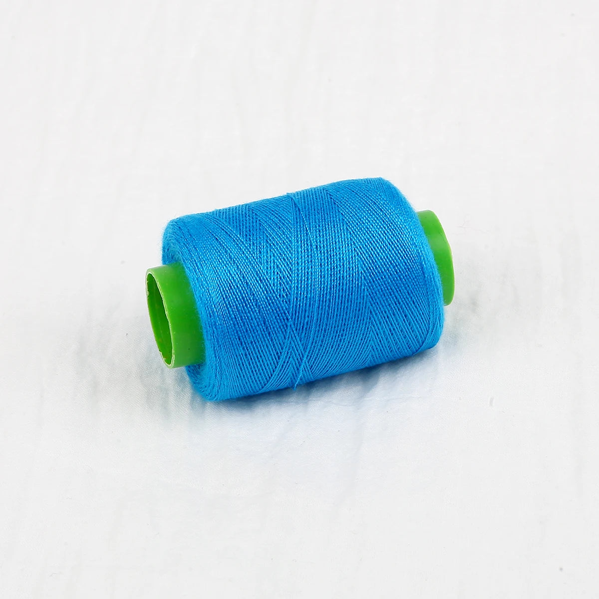 A spool of bright blue sewing thread with a green core.