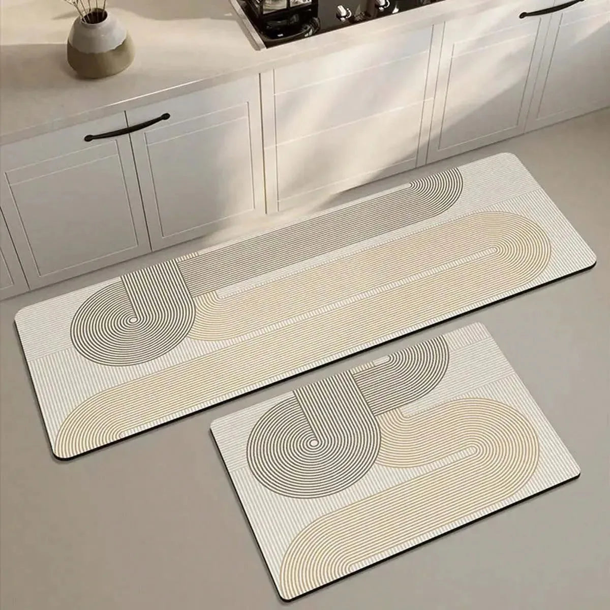 A rectangular beige and white non-slip kitchen floor mat with concentric line patterns is displayed on a light gray counterto