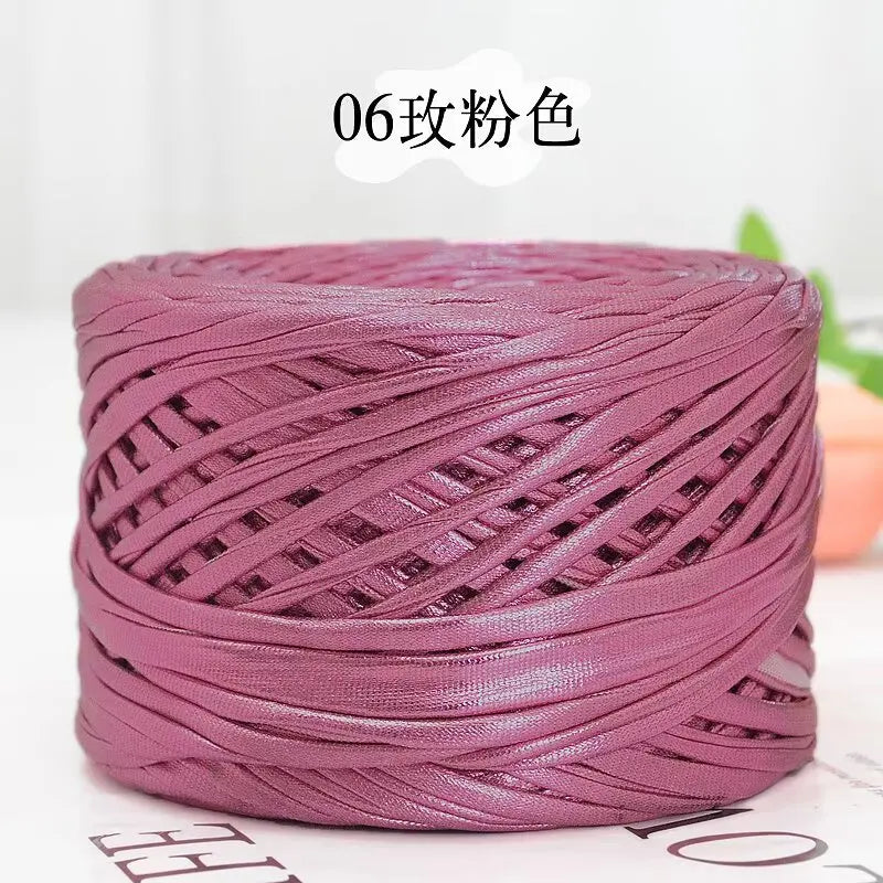 A spool of metallic purple cake yarn used for crafting.