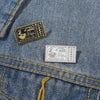 A vintage enamel airline ticket lapel pin featuring a design with the text Have a nice trip.