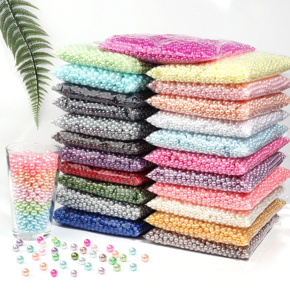 A collection of various colored imitation pearl beads arranged in rows and scattered on a white surface.