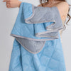 A light blue quilted blanket with gray trim is draped over a person's shoulder.