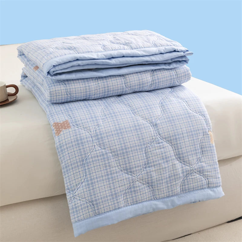 Light blue plaid quilted duvet cover folded on a white surface.