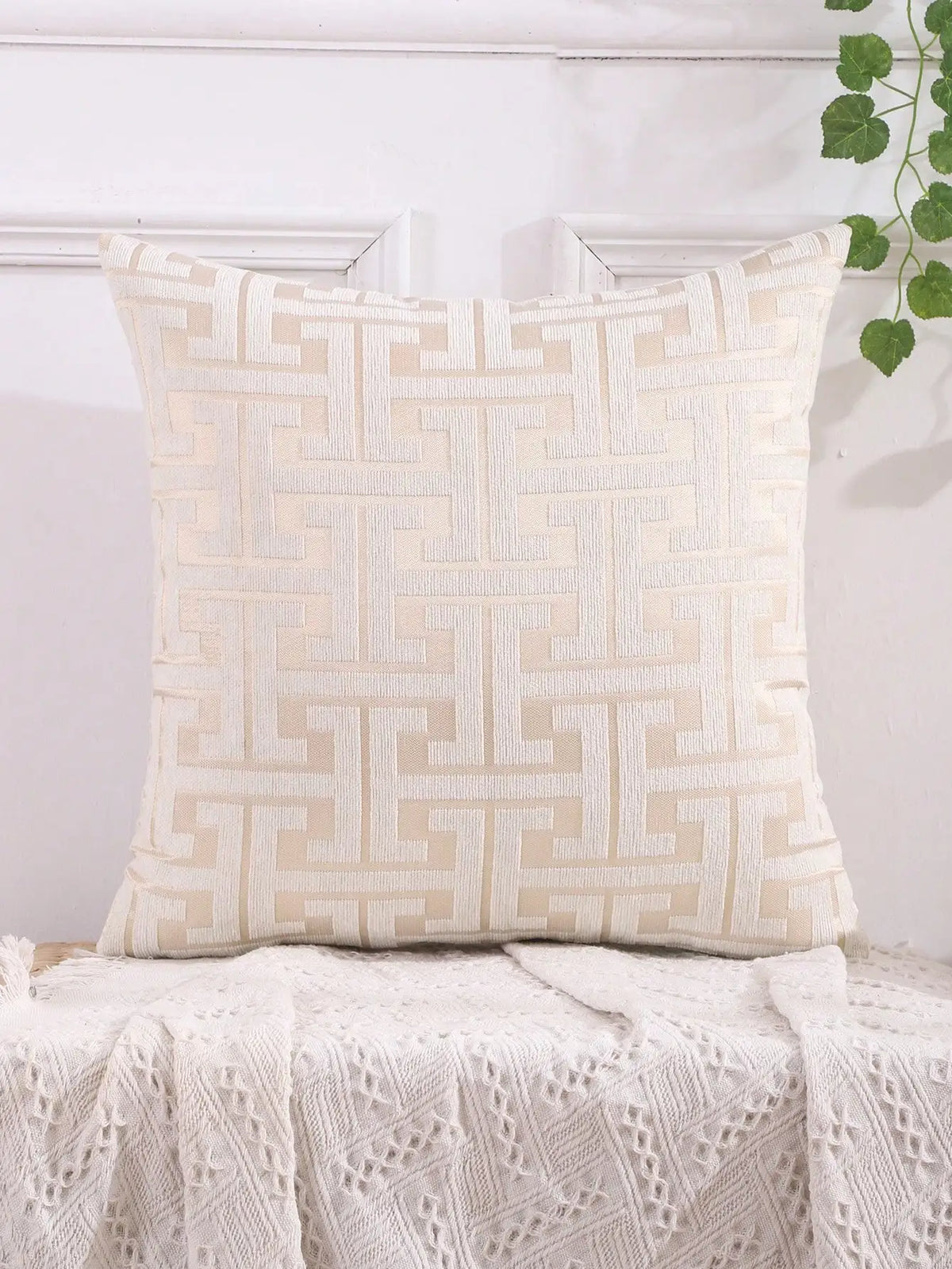 A cream-colored throw pillow cover featuring a geometric Greek key pattern embroidery on a white background.