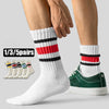 A pair of white crew socks with black and red horizontal stripes is shown on a foot, next to a hand.