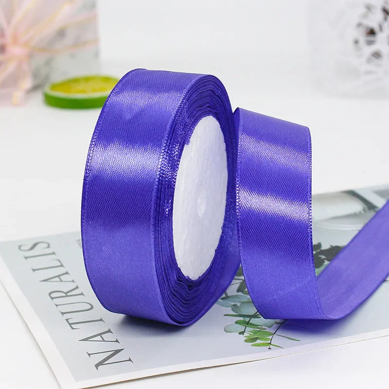 Roll of vibrant purple satin craft ribbon with white filling shown on a sheet of paper