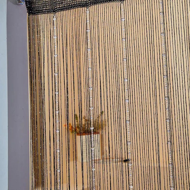 Close-up of decorative crystal beaded string curtains with vertical strands in a gold tone.