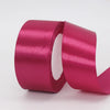 A roll of vibrant magenta satin craft ribbon with a white core.