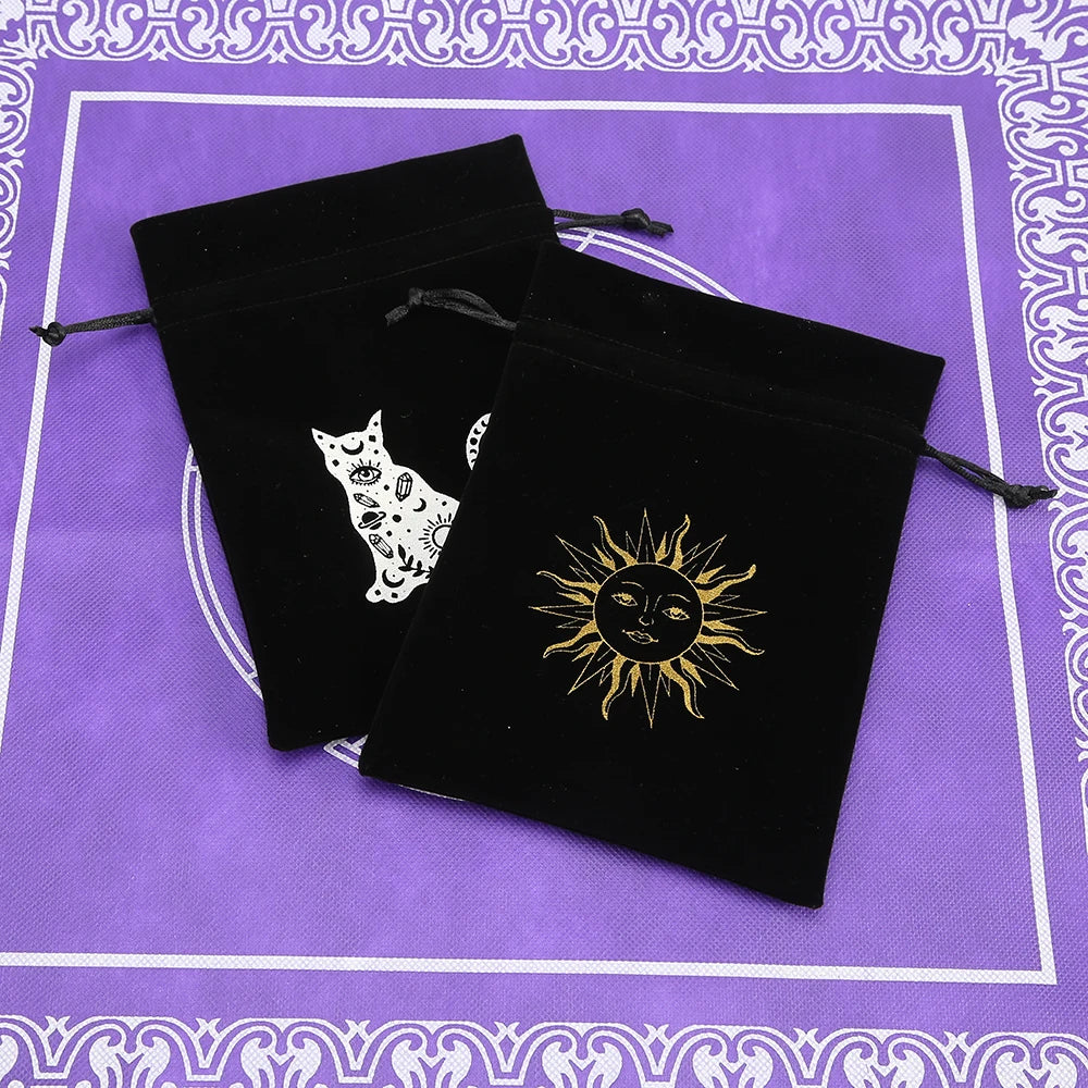 Two black velvet tarot cards storage pouches with white silhouette designs resting on a purple patterned surface.
