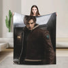 A person holds up a large graphic throw blanket featuring a portrait of a man in a leather jacket.