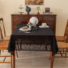 Elegant black lace tablecloth with floral embroidery set on a wooden dining table.