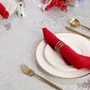 A festive table setting featuring a red napkin, gold cutlery, and white plates on a silver glitter tablecloth.