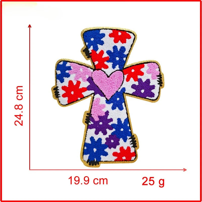 A cross-shaped embroidery patch featuring a pink heart in the center with red and purple floral designs on a white background