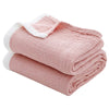 Pink muslin throw blanket folded and rolled with white trim