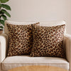 A set of two leopard print throw pillows on a light-colored sofa.