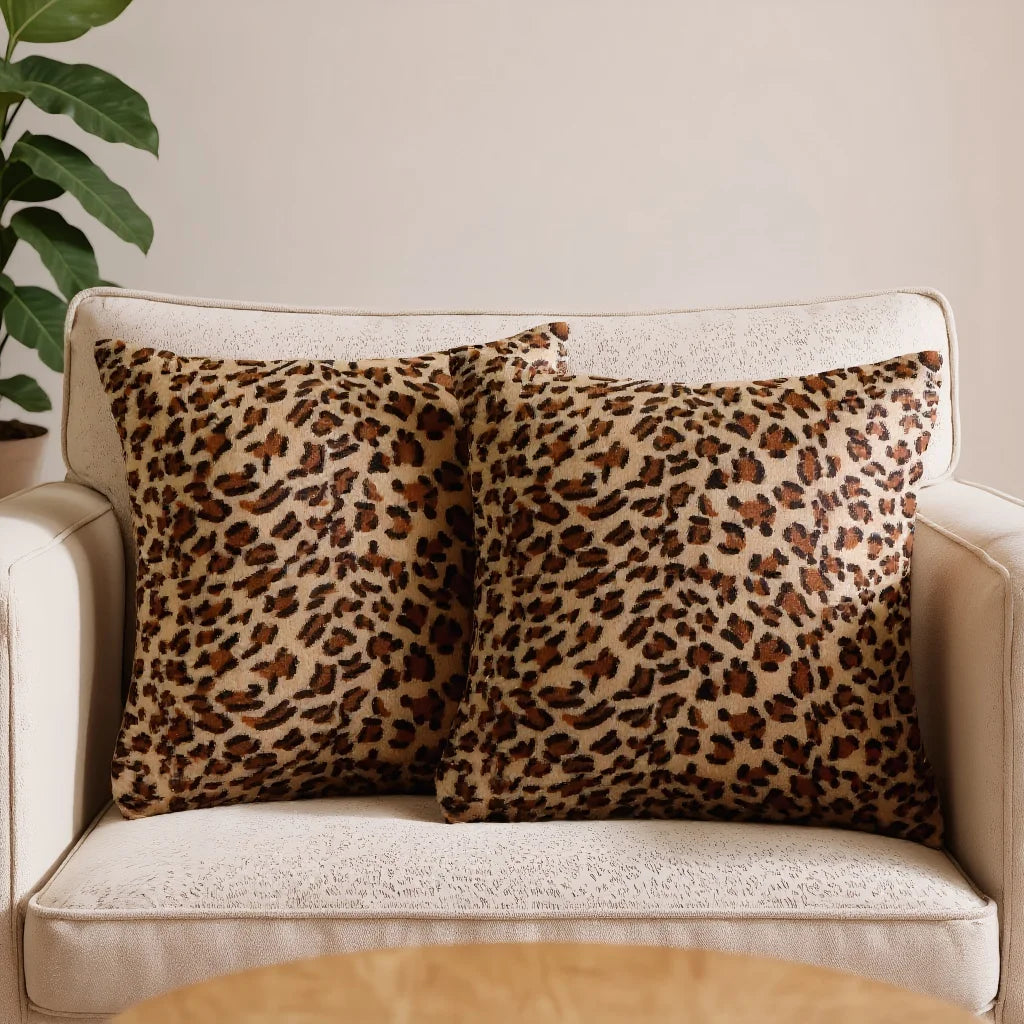 A set of two leopard print throw pillows on a light-colored sofa.