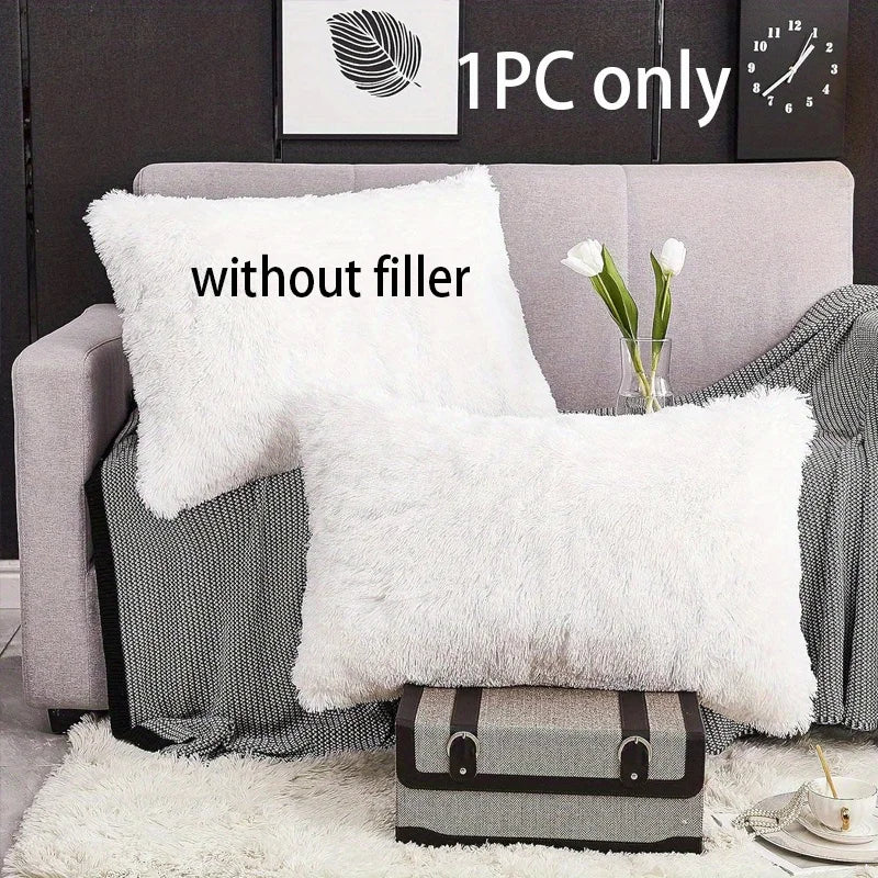 White faux fur pillow covers displayed on a gray sofa with a white rug and a potted plant.