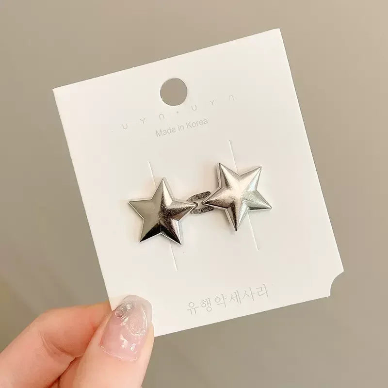 A pair of silver star-shaped metal brooch pins displayed on a white card.