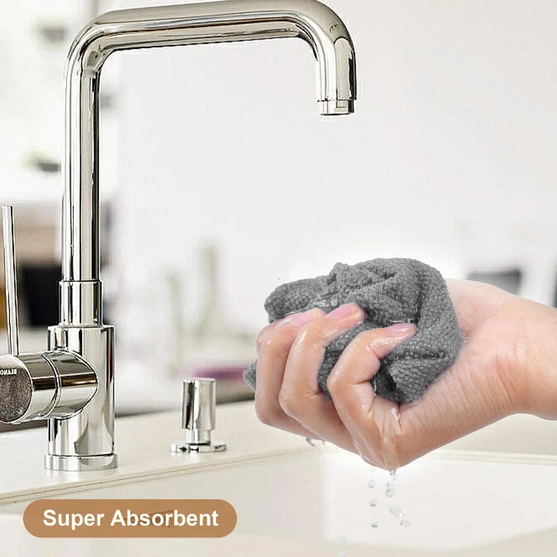 A hand is using a reusable microfiber cleaning wipe to clean a modern stainless steel kitchen faucet.