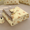 A folded light yellow quilt with a beige cover and a gray lining, featuring small brown animal patterns.