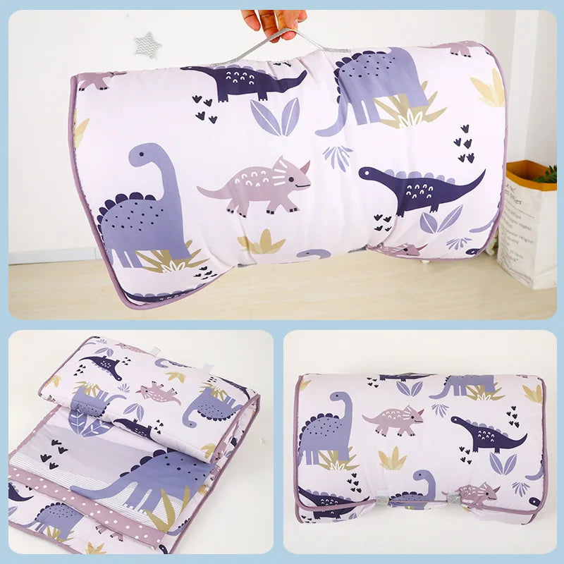 A set of purple and green dinosaur patterned toddler nap mats, including a pillow and fleece blanket.