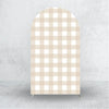 A tall arch backdrop cover with a beige and white gingham pattern displayed against a gray wall.