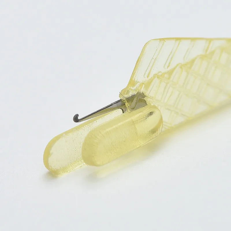 A close-up of a mini hand sewing needle threader kit with a translucent yellow plastic body and metal tip.