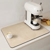 A white espresso machine sits on a beige drain mat next to a cup of coffee.