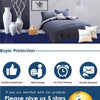 A dark blue bed with a striped duvet and pillows featuring a black and white pattern, set against a gray wall.