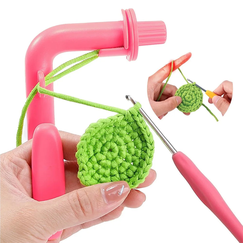 A pink crochet tool and tension regulator set with green yarn visible in a hand.