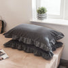 A set of two soft plaid washed cotton pillowcases with ruffled edges displayed on a light-colored surface.