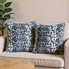 A set of two leopard print throw pillow covers with black and white spots resting on a light-colored sofa.