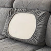 A close-up of a gray leaf pattern sofa slipcover featuring a square white cushion.