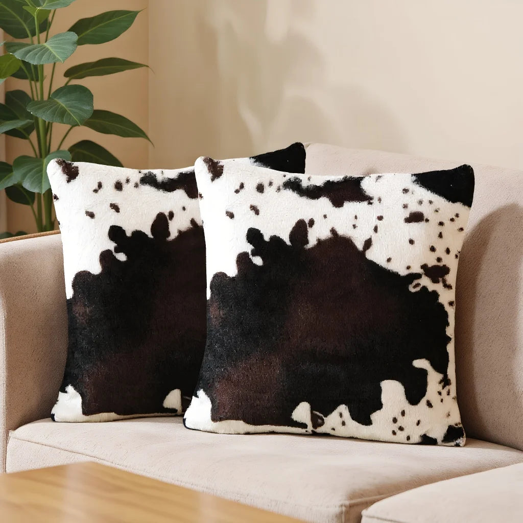 A set of two throw pillows featuring a black and white leopard print design on a neutral sofa.