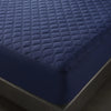 A close-up view of a dark blue quilted mattress protector on a bed.