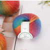 A ball of multi-colored wool yarn featuring shades of orange, pink, blue, and purple, displayed on a white surface.