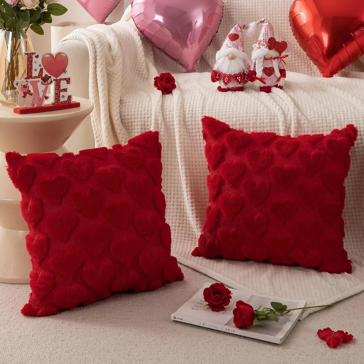 A set of red heart embroidery plush cushions and a pink heart balloon on a white textured fabric.