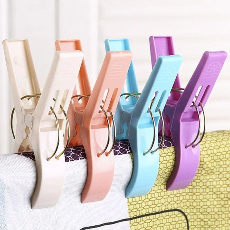 A pack of four large plastic clothes pins in various colors including beige, pink, blue, and purple.