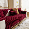 A deep red plush rabbit sofa cushion draped over a white sofa with a fluffy white rug.