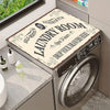 A close-up view of a stainless steel laundry room appliance with a decorative sign on the lid.