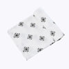 A white muslin swaddle blanket with a black snowflake pattern folded diagonally.